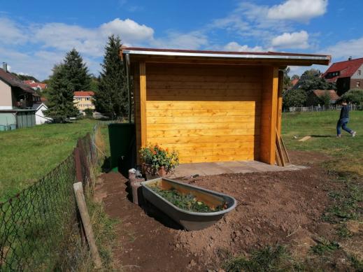 Das Gartenhaus als Garage für den Rasentraktor fügt sich in die Umgebung ein